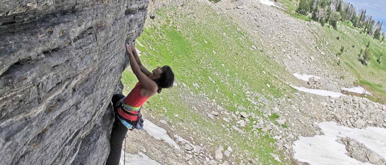 Climber on Neanderthal Silhouette at Happy Hour Wall, Jackson Hole Mountain Resort — alpine sport above snow and meadow