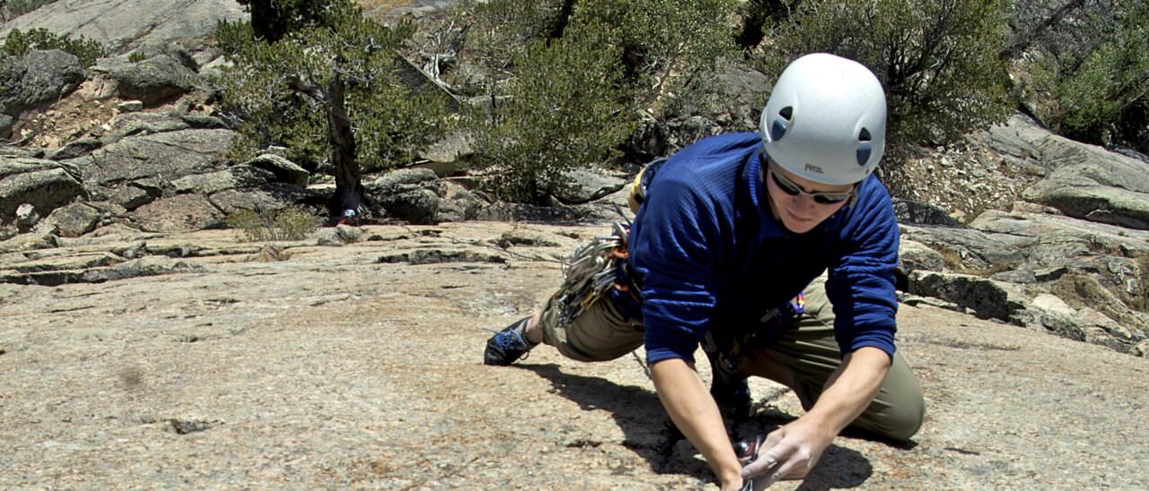 Climber placing gear on the granite crack El Dorado at Scab Creek Buttress, Wind River Range