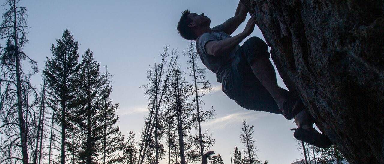 Boulderer looking up on a steep problem at dusk — WYdaho / Badger Creek bouldering